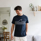 Homme debout dans un appartement portant un tee-shirt bio bleu marine avec une vague mâle de mer